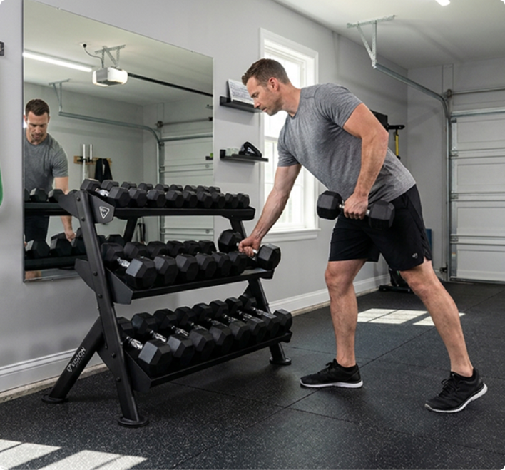 Man lifting weights off a Vision Home Fitness 400-ADBR Adjustable Dumbbell Rack in a garage gym